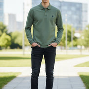 Green polo shirt with a brand logo on a hanger in a clothing store.