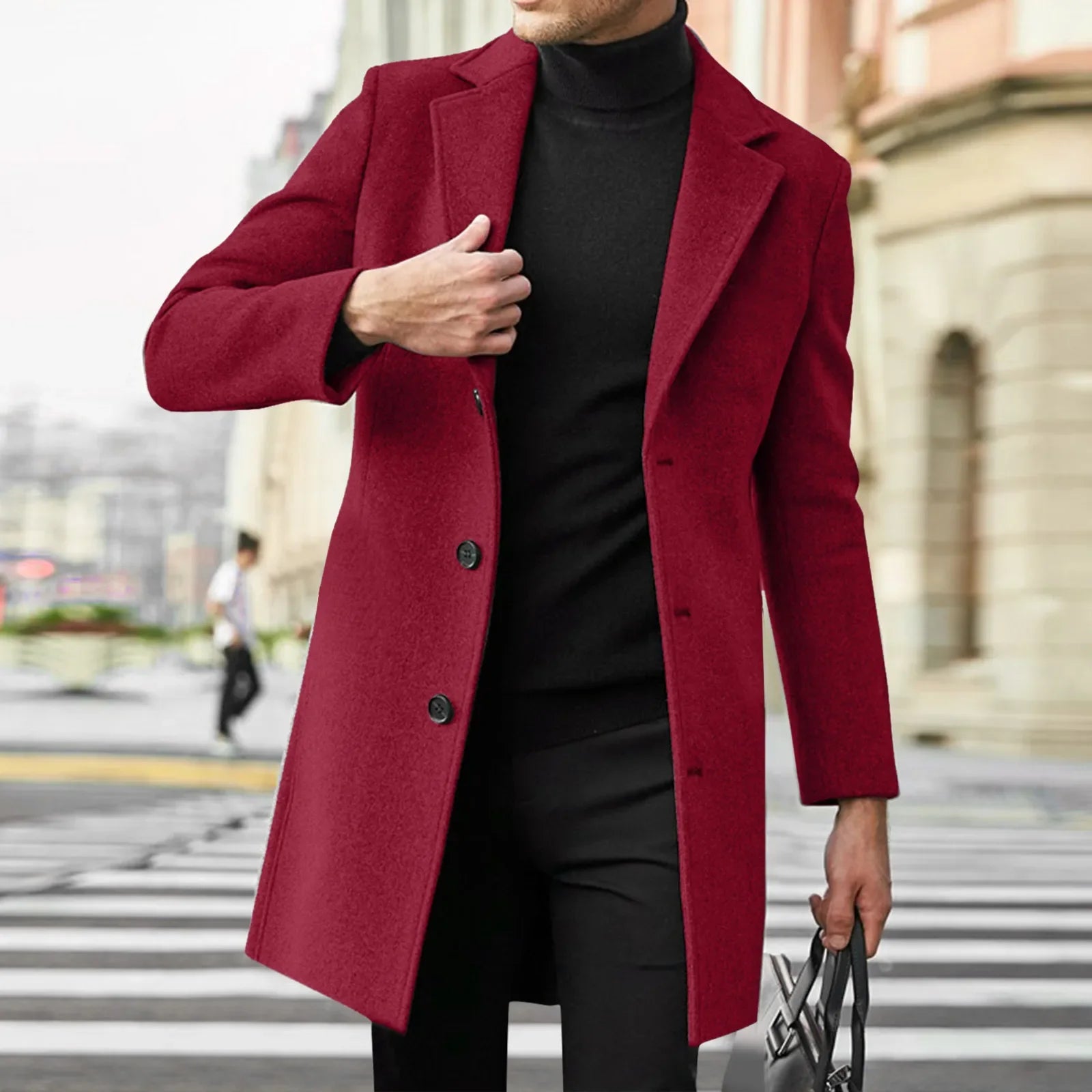 Person wearing a red coat over a black outfit on a city street.