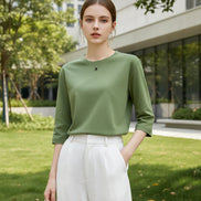 Person wearing a green top and white pants against a neutral background