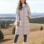 Woman wearing a long beige puffer coat in an urban setting.