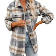 Woman wearing a gray and cream plaid shirt with a white top and jeans, against a white background.