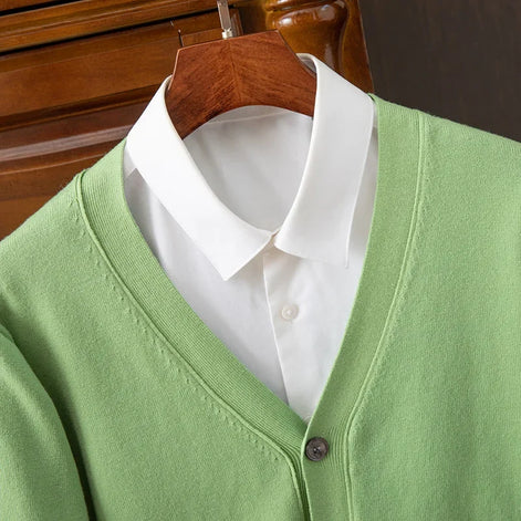 Green cardigan over a white shirt on a wooden hanger