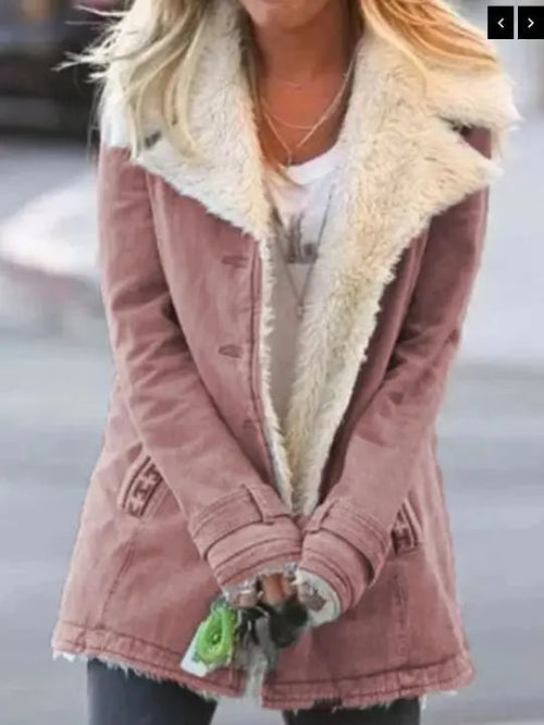 Woman outdoors wearing a dusty rose coat with wide cream fleece-look lapels, front pockets and cuff tabs over a white top