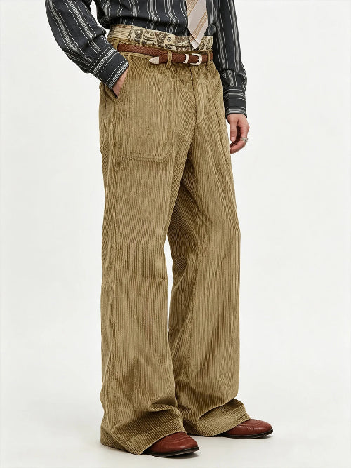 A person wearing wide-leg tan corduroy trousers with a brown belt, a striped shirt, and brown shoes, photographed against a plain light background.