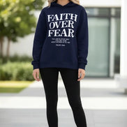 Navy blue hoodie with 'Faith Over Fear' text on a wooden surface with shoes and a cone.