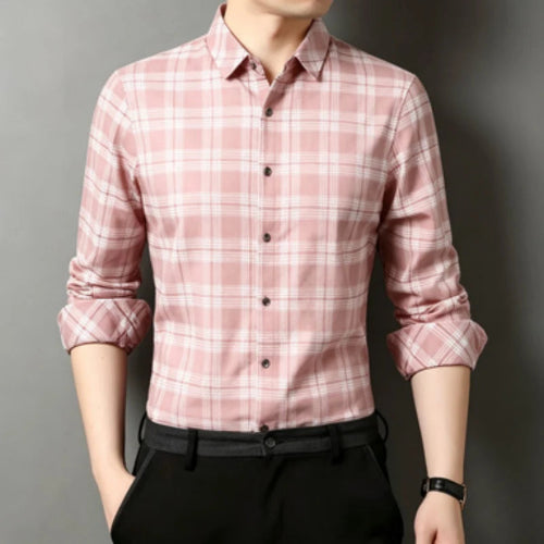 A man wearing a pink and white plaid long-sleeve button-down shirt with black trousers, shown from the chin down against a dark gray studio background.