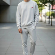 Person wearing a white sweatshirt with a small red logo on a light gray background