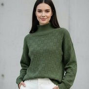 A woman wearing a textured olive green mock-neck knit sweater with a checkerboard pattern, 