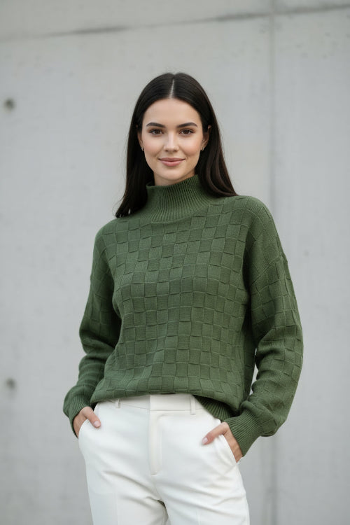 A woman wearing a textured olive green mock-neck knit sweater with a checkerboard pattern, 
