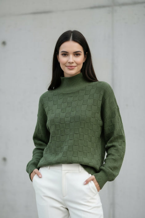 A woman wearing a textured olive green mock-neck knit sweater with a checkerboard pattern, 