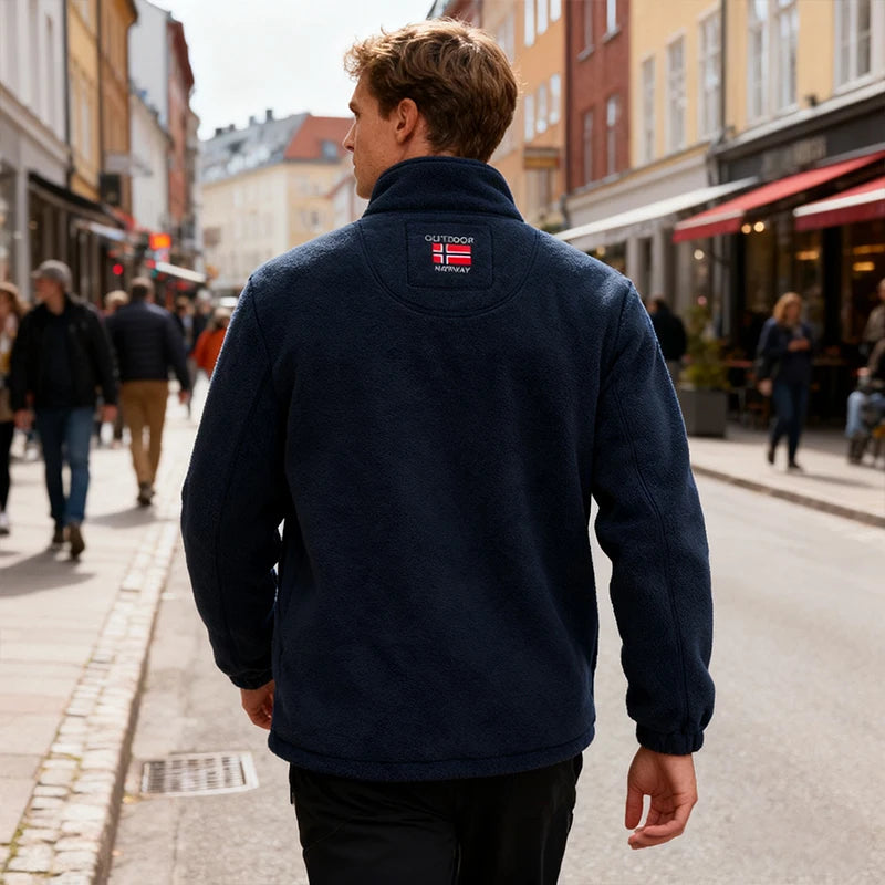 Man wearing a navy blue jacket with a brand logo on a city street