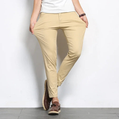 Person wearing beige pants and brown shoes on a plain background