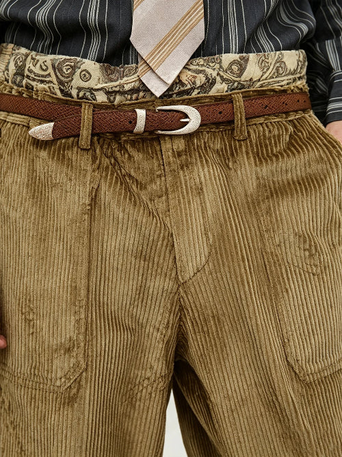 Close-up of a person wearing brown corduroy trousers, a brown belt with a silver buckle, a patterned waistband, a striped shirt, and a striped tie.