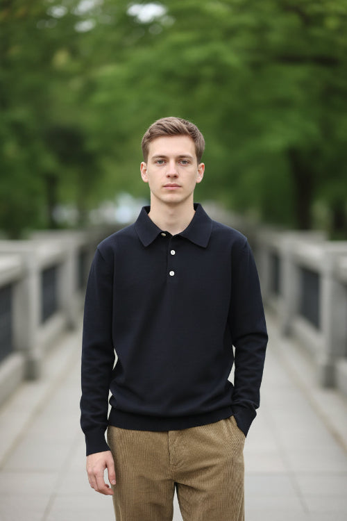 Person wearing a black long-sleeve polo shirt with a collar against a green background