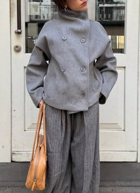 Front view of a woman wearing a gray double-breasted coat with matching pleated trousers