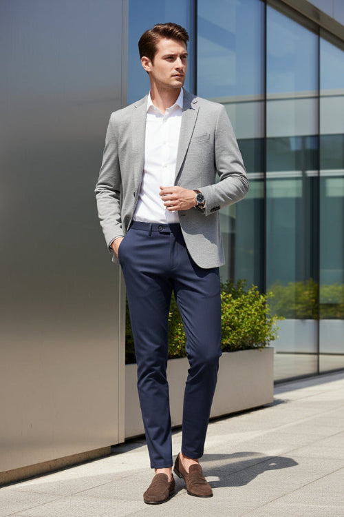 A pair of dark slate blue trousers hanging on a black hanger against a light gray background with a dramatic diagonal shadow.