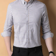 Person wearing a checkered shirt with rolled-up sleeves against a beige background