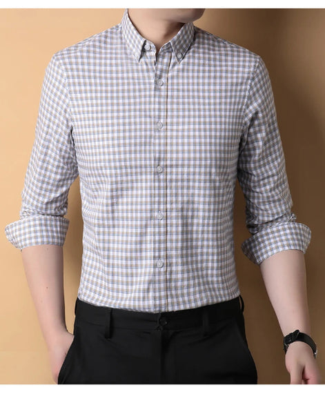 Person wearing a checkered shirt with rolled-up sleeves against a beige background