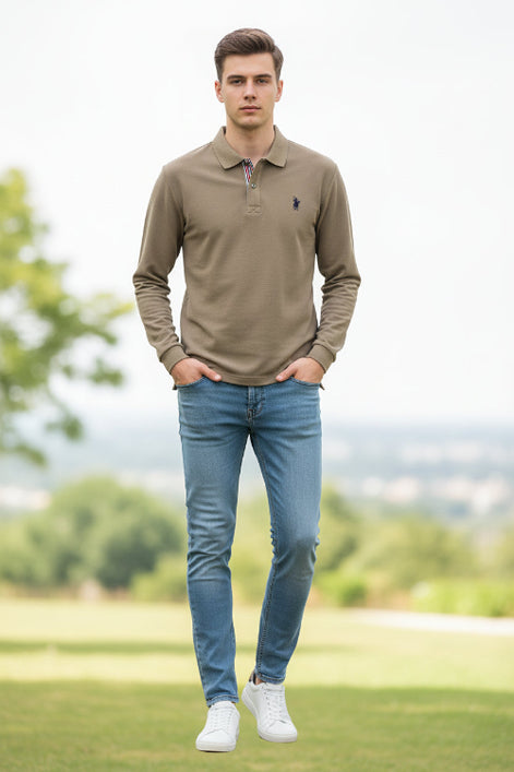 Beige polo shirt with a brand logo held by a hand, with a blurred background of books and shirts.