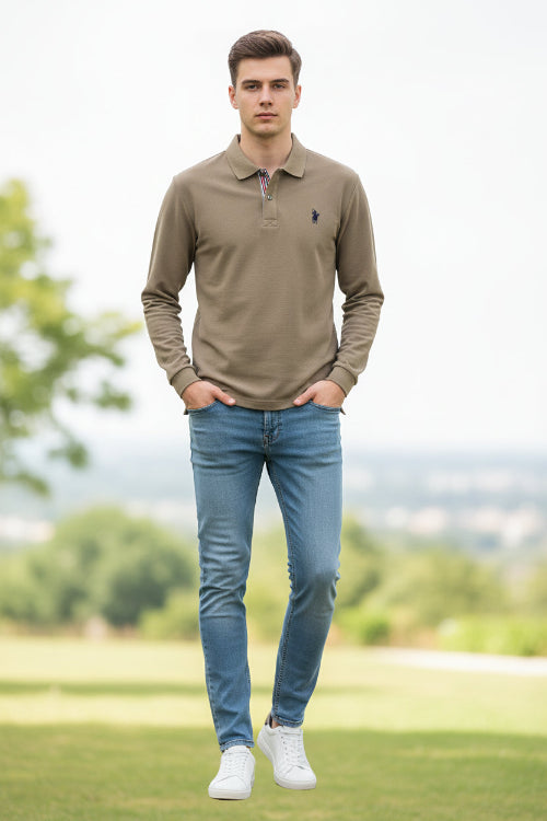 Beige polo shirt with a brand logo held by a hand, with a blurred background of books and shirts.