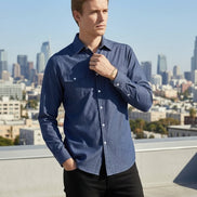 Man wearing a blue shirt on a rooftop with a city skyline in the background
