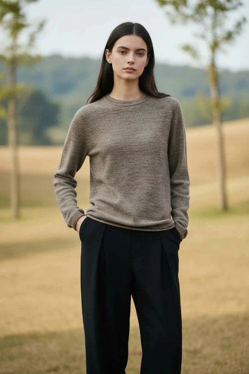 A woman wearing a long-sleeve crewneck knit sweater in a heathered taupe-brown color,