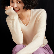 Woman wearing a cream cashmere sweater with a black background