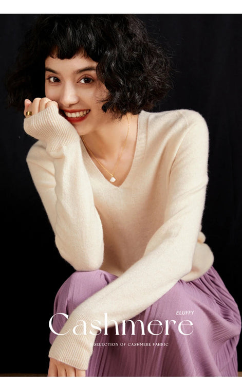 Woman wearing a cream cashmere sweater with a black background
