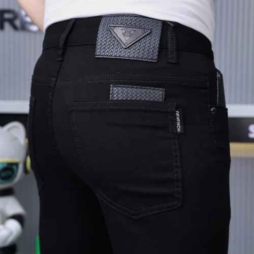 Close-up rear view of a person wearing black jeans with a textured gray triangular patch on the back waistband and a matching patch 