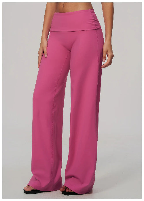 A model wearing bright pink wide-leg pants with a high-waisted wrap-style waistband, shown from the waist down against a light gray studio background.