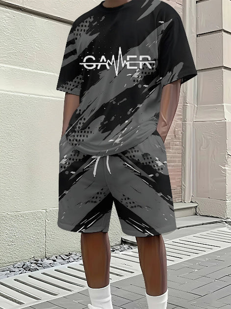 A person wearing a black and gray camouflage-patterned t-shirt and matching shorts with a white 'GAMER' graphic on the chest, 
