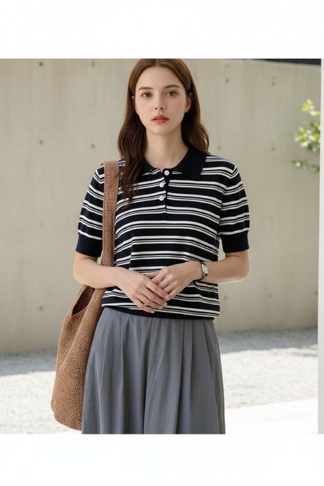 Person wearing a black and white striped shirt with a brown bag indoors.