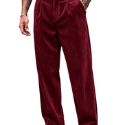 A person wearing loose-fitting corduroy trousers in deep burgundy, styled with a black belt, black top, and black-and-white shoes against a plain white background.