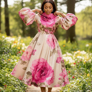 Woman wearing a floral dress with pink flowers holding a gold clutch against a white background