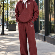 A man wearing a matching Reebok waffle-knit hoodie and sweatpants set in a dusty burgundy red color, shown against a plain white background.