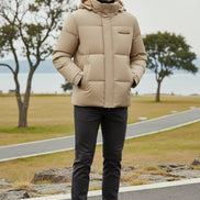 A man wearing a beige hooded puffer jacket with a black turtleneck underneath, shown against a dark gray background with feature callouts on the left.