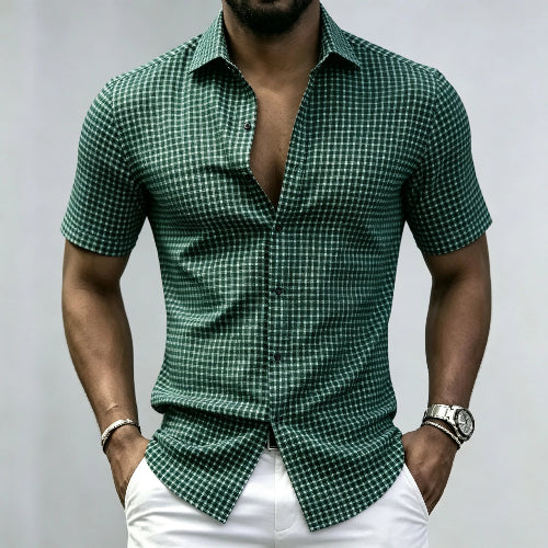 A man wearing a green and white checkered short-sleeve button-up shirt with white pants, 