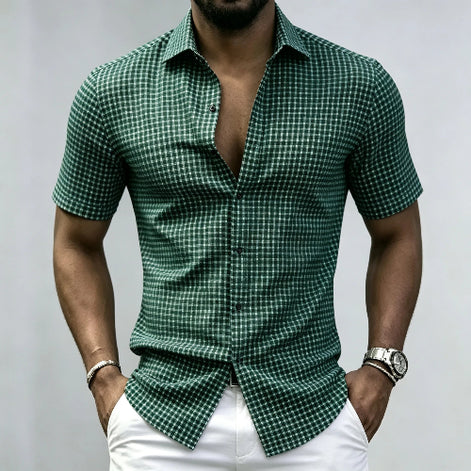 A man wearing a green and white checkered short-sleeve button-up shirt with white pants, 