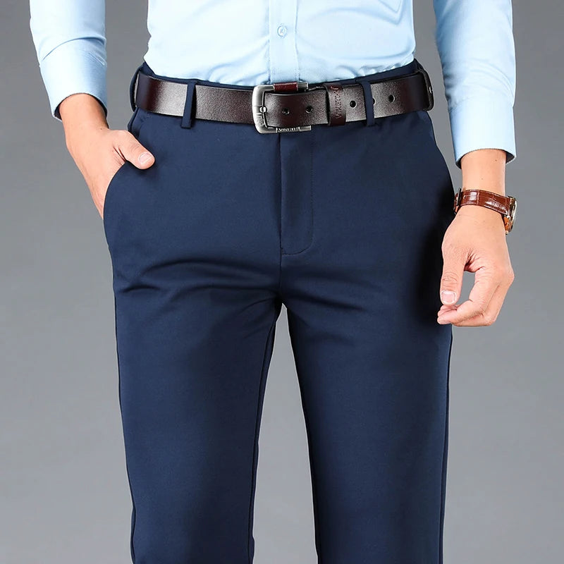 Person wearing navy pants with a brown belt on a gray background