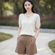 Woman wearing a white textured sweater and brown pants outdoors