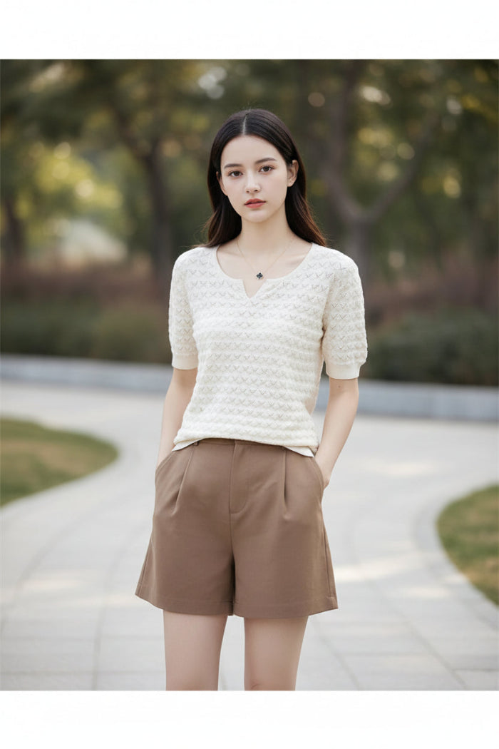 Woman wearing a white textured sweater and brown pants outdoors