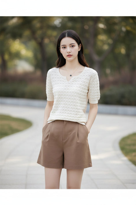 Woman wearing a white textured sweater and brown pants outdoors