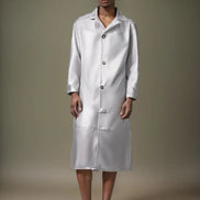 Person wearing a long white lab coat against a neutral background