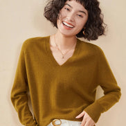 Woman wearing a mustard yellow cashmere sweater on a beige background