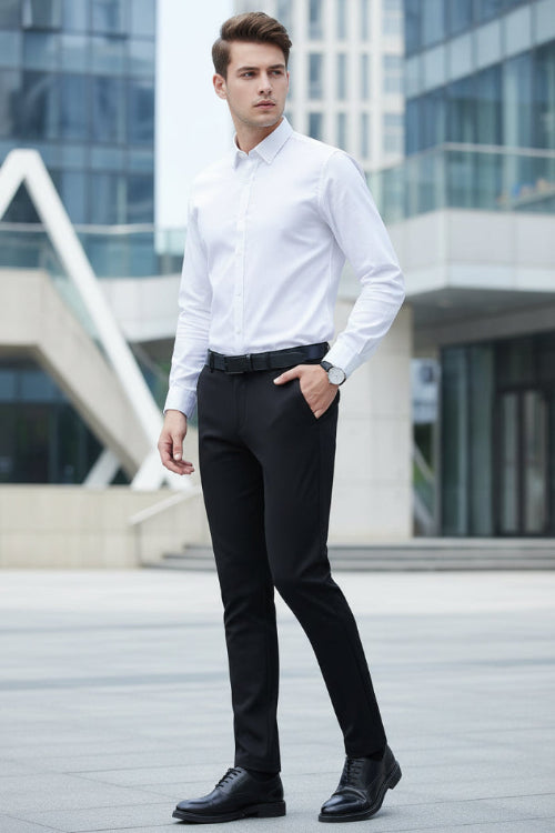 A man wearing slim-fit black dress pants with a white button-down shirt and black dress shoes, shown from the waist down against a dark gray studio background. 