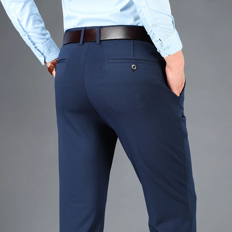 Navy blue pants worn with a light blue shirt on a gray background