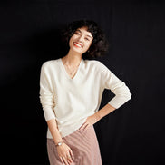 Woman wearing a white sweater and pink skirt against a black background