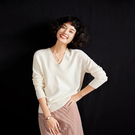Woman wearing a white sweater and pink skirt against a black background