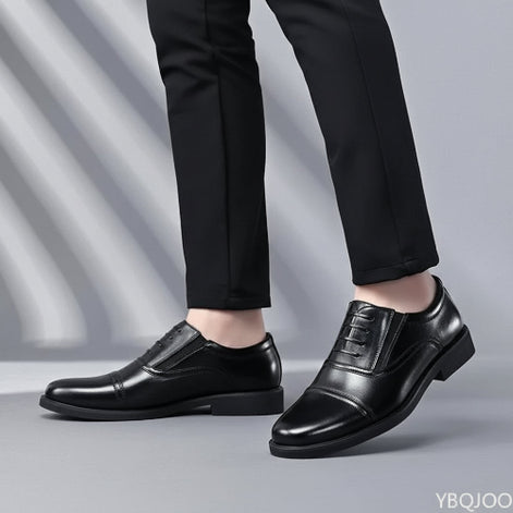 Black leather dress shoes worn with black pants on a gray background