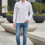 White long-sleeve polo shirt with a brand logo on a hanger against a clothing rack background.